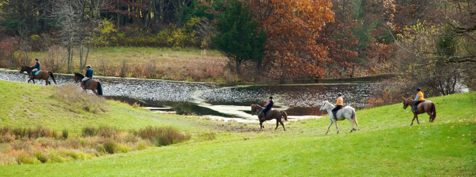 Horses and riders trail riding by lake at Carlette Farm